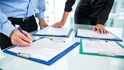 Healthcare professionals reviewing contract documents with digital compliance tools